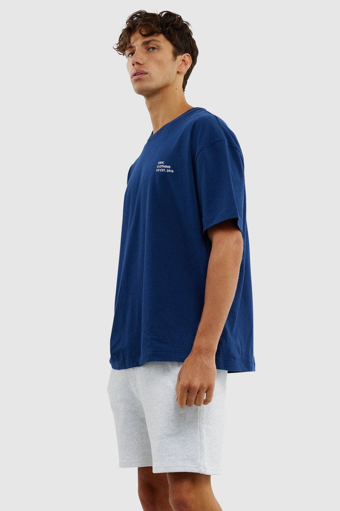 Side view of model wearing navy boxy tshirt with white logo