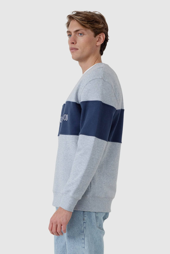 Side view of Male model wearing grey crew neck with navy middle panel with white embroidered ORTC Clothing co