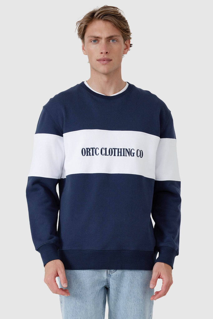 Male model wearing navy crew neck sweater with white middle panel and navy embroidered ORTC Clothing co