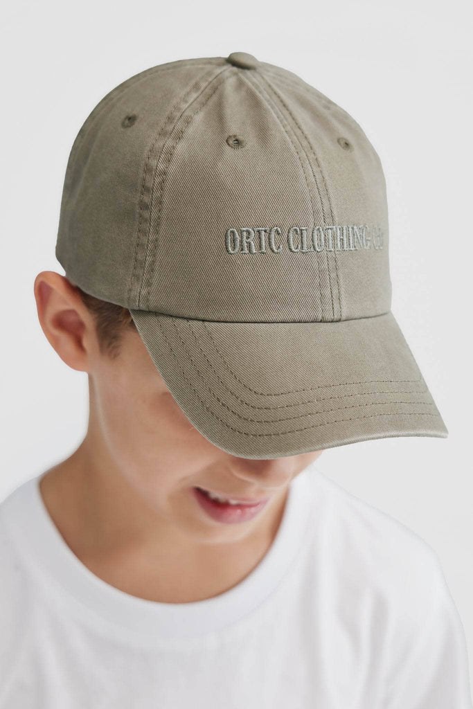 Child model wearing olive green baseball cap with olive embroidered ORTC CLOTHING CO