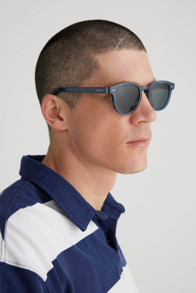 Model wearing clear navy blue sunglasses with ortc on arm